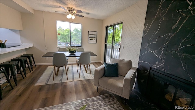 12506 E Cornell Ave Unit 201, Aurora, CO 80014 - dining area with ceiling fan, a textured ceiling, wood finished floors, an accent wall, and baseboards