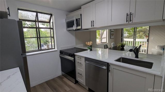 12506 E Cornell Ave Unit 201, Aurora, CO 80014 - kitchen featuring appliances with stainless steel finishes, a sink, wood finished floors, light stone countertops, and white cabinets