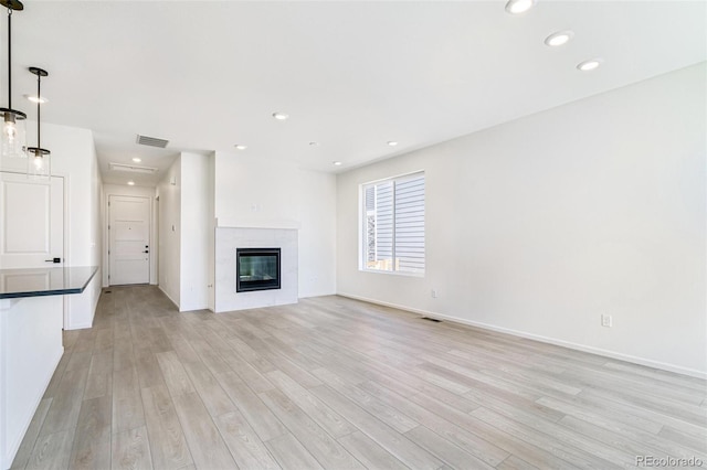 unfurnished living room featuring a tile fireplace and light wood-type flooring