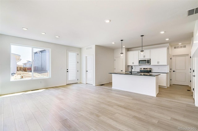 kitchen featuring sink, light wood-type flooring, stainless steel appliances, decorative light fixtures, and white cabinets