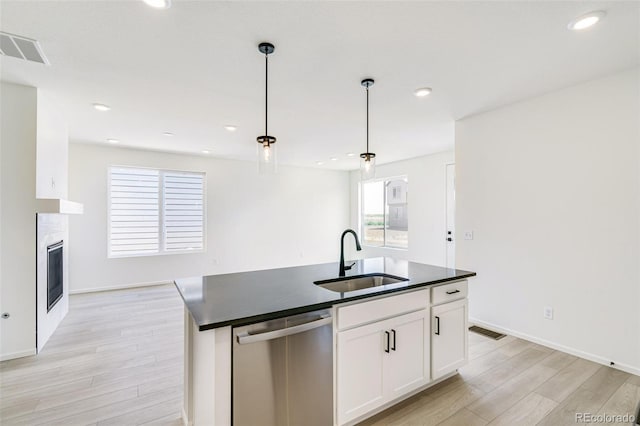 kitchen featuring sink, dishwasher, an island with sink, hanging light fixtures, and white cabinets