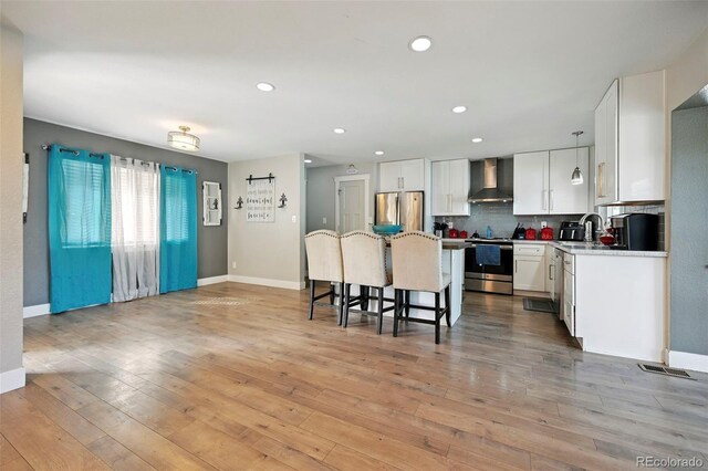 3340 Afternoon Cir, Colorado Springs, CO 80910 - kitchen featuring wall chimney range hood, appliances with stainless steel finishes, a breakfast bar, backsplash, and white cabinetry