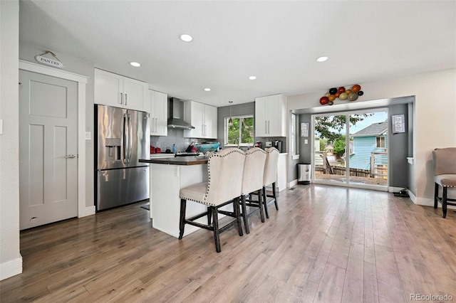 3340 Afternoon Cir, Colorado Springs, CO 80910 - kitchen featuring stainless steel fridge with ice dispenser, a breakfast bar area, white cabinetry, wall chimney range hood, and recessed lighting