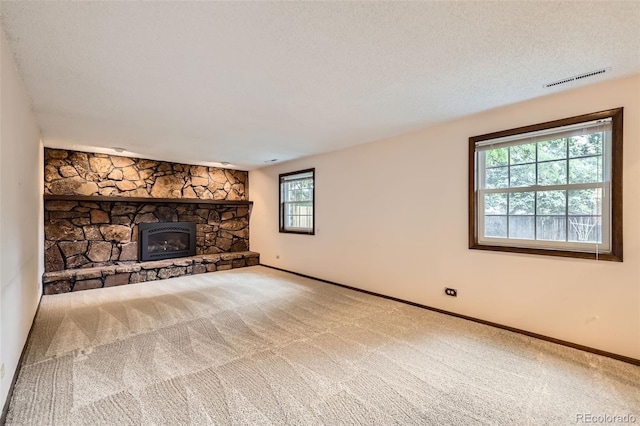 2556 S Eagle Cir, Aurora, CO 80014 - unfurnished living room with carpet, a stone fireplace, baseboards, and a textured ceiling