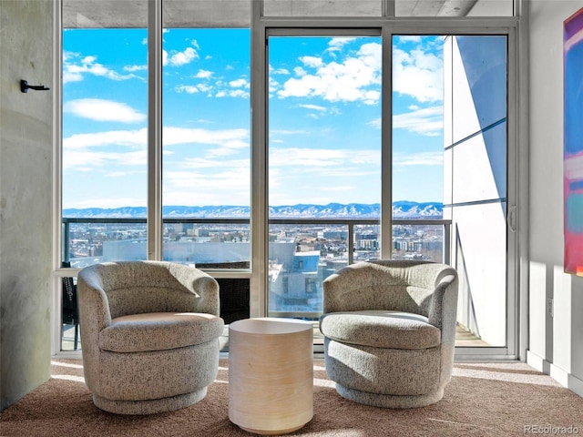 living area with a mountain view, a wall of windows, and carpet flooring