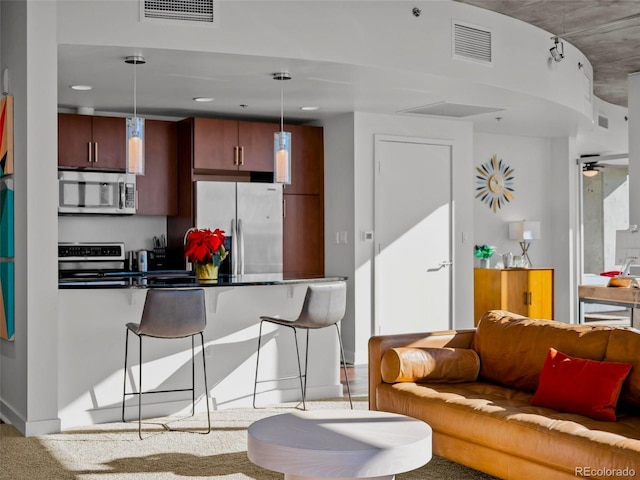 kitchen featuring pendant lighting, ceiling fan, stainless steel appliances, and a kitchen breakfast bar