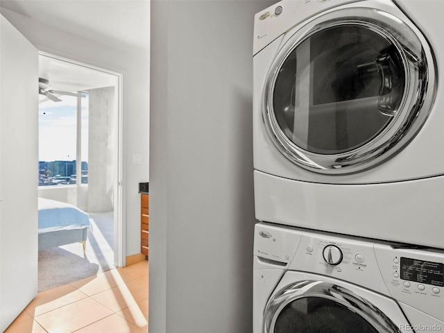 clothes washing area with stacked washer and clothes dryer, light tile patterned floors, and ceiling fan