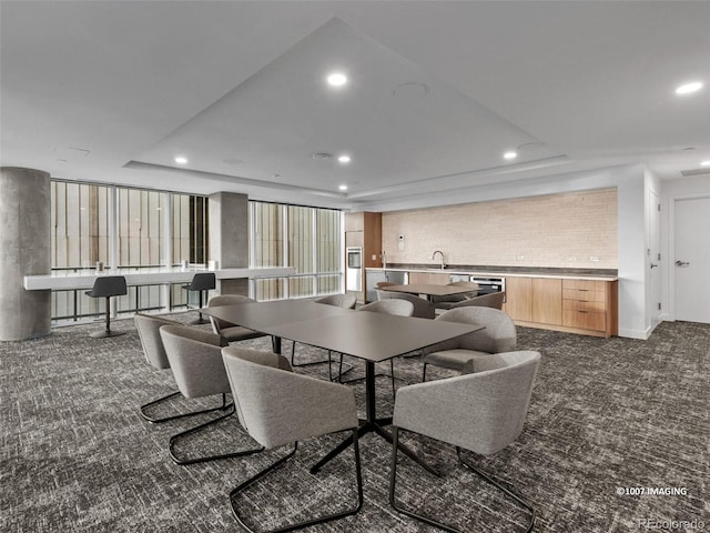 carpeted dining space featuring a tray ceiling and sink