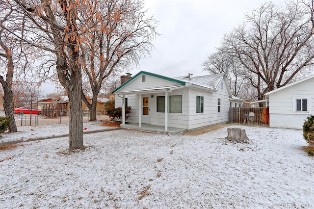 view of front of house featuring a chimney, a patio area, and fence