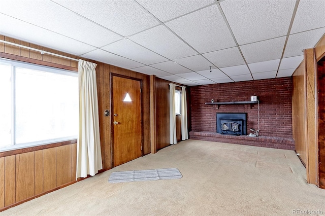 unfurnished living room featuring carpet floors, wood walls, and a paneled ceiling