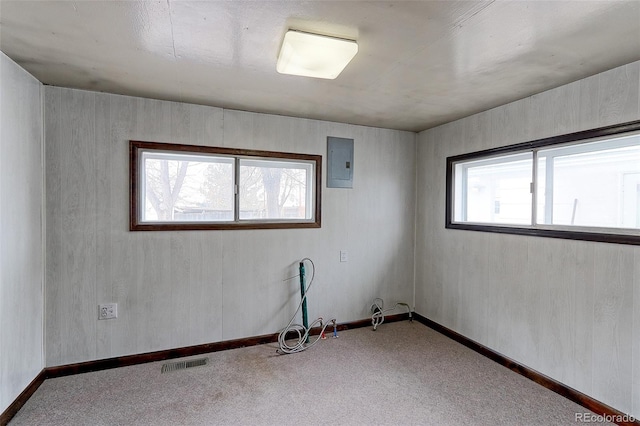 carpeted spare room featuring visible vents, electric panel, and baseboards