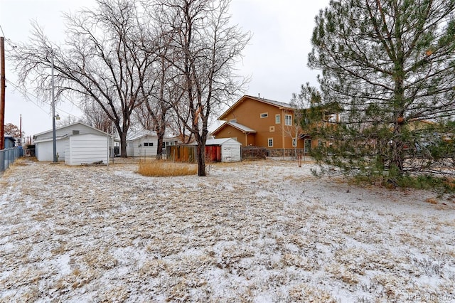 yard covered in snow with an outbuilding, fence, and a storage shed