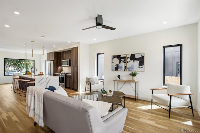 living room with sink, ceiling fan, and light hardwood / wood-style floors