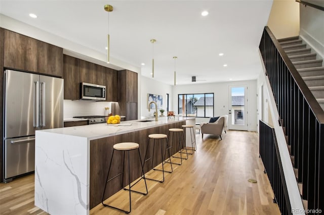 kitchen featuring appliances with stainless steel finishes, decorative light fixtures, tasteful backsplash, sink, and a spacious island