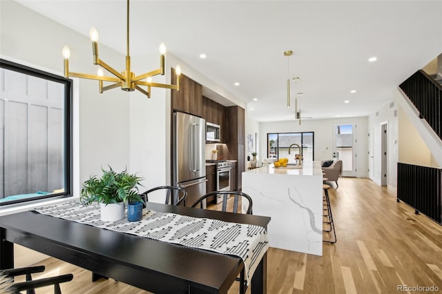 dining area with sink, an inviting chandelier, and light hardwood / wood-style flooring