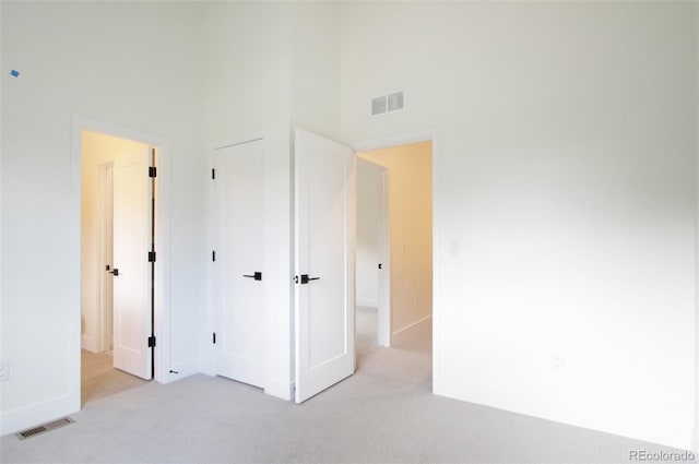 unfurnished bedroom with a towering ceiling and light carpet