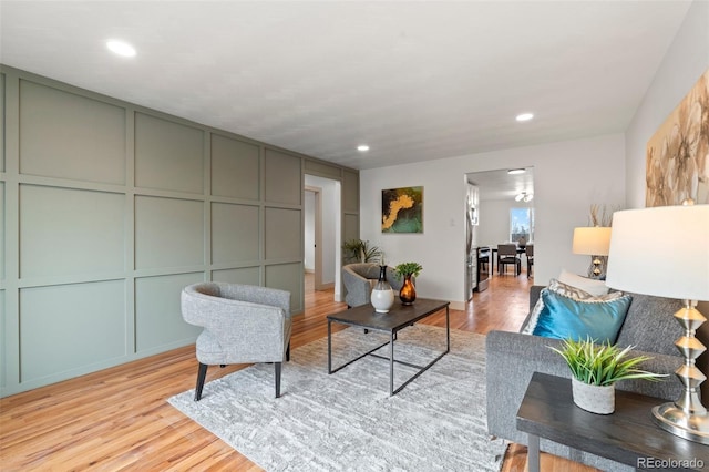 living room with light wood-type flooring, a decorative wall, and recessed lighting