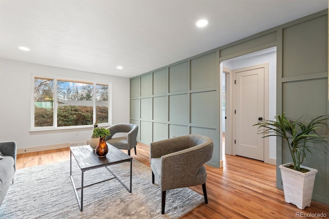 living area featuring light wood-style floors, recessed lighting, and a decorative wall