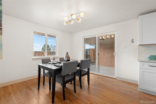 dining area featuring light wood-style floors, a chandelier, and baseboards