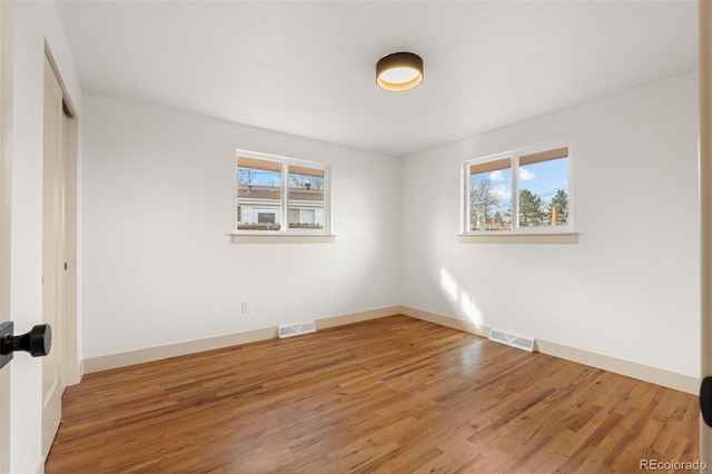 spare room featuring visible vents, baseboards, and wood finished floors