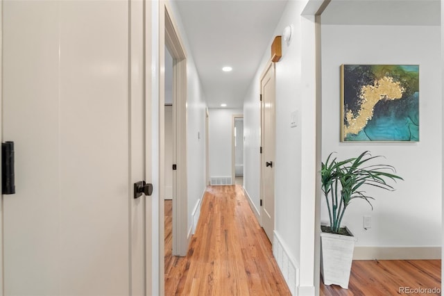 corridor featuring light wood-style flooring, recessed lighting, visible vents, and baseboards