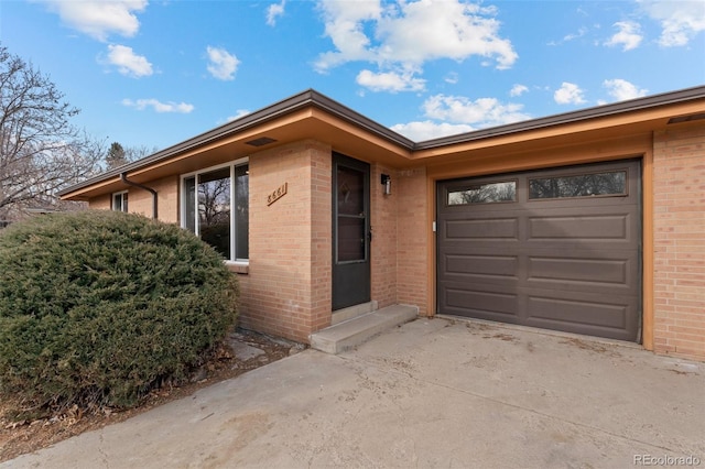 property entrance featuring concrete driveway, brick siding, and an attached garage