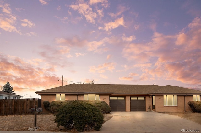 ranch-style house with a garage, concrete driveway, brick siding, and fence