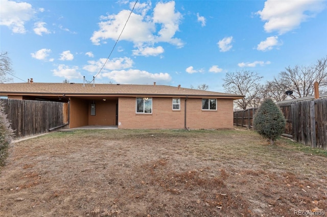 rear view of house with a fenced backyard, brick siding, and a lawn