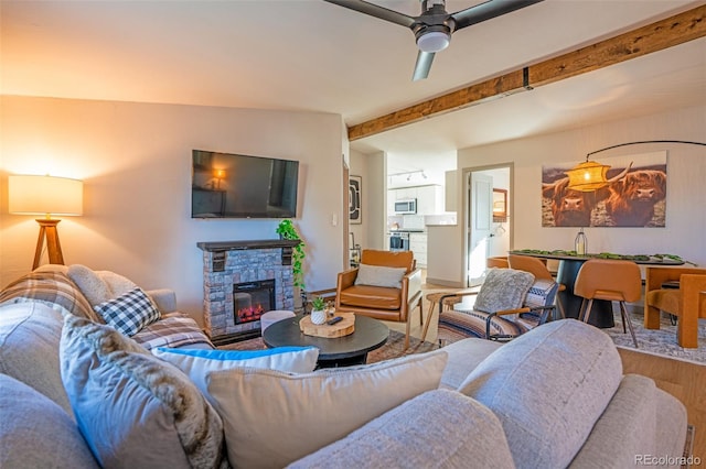 living area featuring a fireplace, lofted ceiling with beams, wood finished floors, and ceiling fan