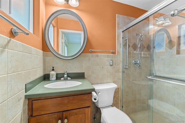 bathroom featuring tile walls, toilet, a shower with door, and vanity