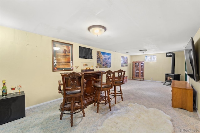 dining space with a wood stove, indoor bar, and light colored carpet