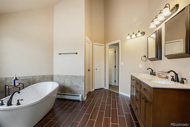 2100 Elk Rdg, Divide, CO 80814 - bathroom featuring a baseboard radiator, a soaking tub, double vanity, a high ceiling, and wood finished floors