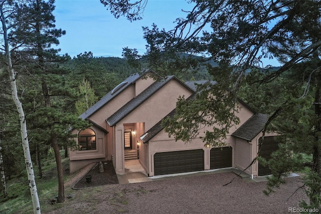 2100 Elk Rdg, Divide, CO 80814 - view of front of home featuring stucco siding, an attached garage, driveway, and a wooded view