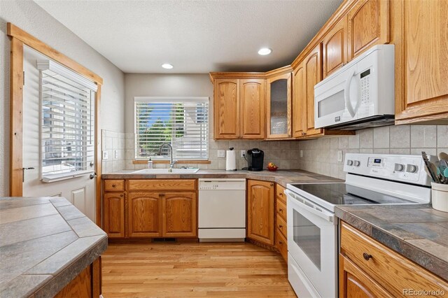 660 Callisto Dr, Loveland, CO 80537 - kitchen with white appliances, a sink, light wood-style floors, tasteful backsplash, and glass insert cabinets
