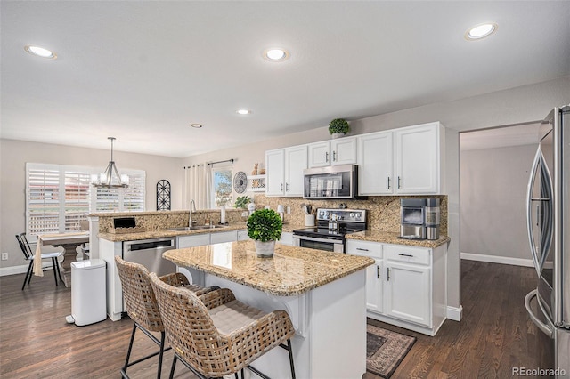 13340 Saint Paul St, Thornton, CO 80241 - kitchen featuring appliances with stainless steel finishes, a peninsula, white cabinetry, a breakfast bar, and dark wood finished floors