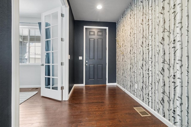 foyer featuring visible vents, baseboards, and wood finished floors