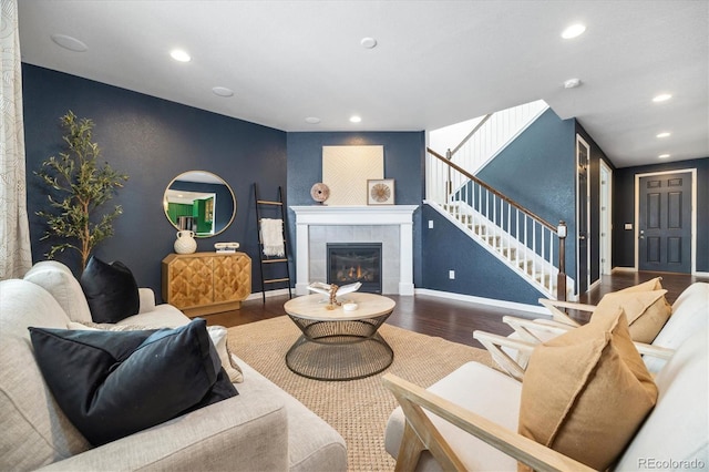 living area featuring recessed lighting, an accent wall, wood finished floors, baseboards, and stairs