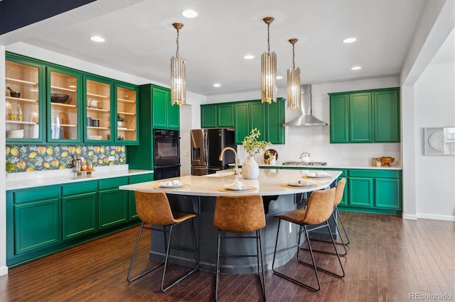 kitchen featuring dark wood finished floors, a breakfast bar area, appliances with stainless steel finishes, light countertops, and wall chimney range hood