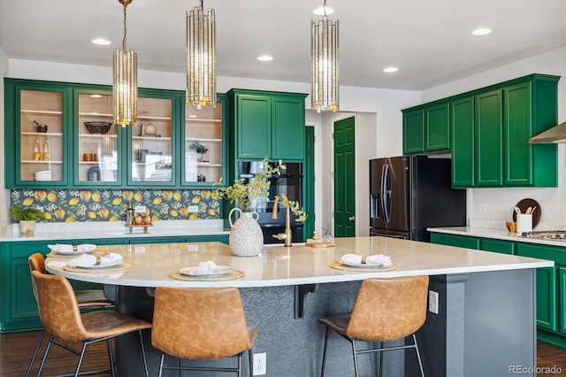 kitchen featuring dark wood-style floors, stainless steel gas stovetop, light countertops, and black fridge with ice dispenser