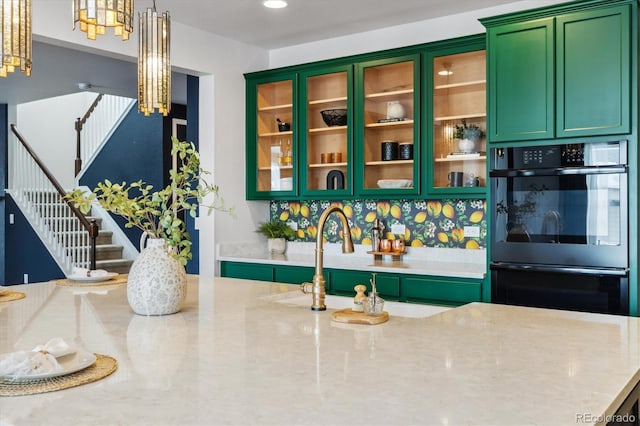 kitchen featuring double oven, recessed lighting, green cabinets, light stone countertops, and glass insert cabinets