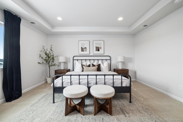 bedroom with a tray ceiling, carpet, visible vents, and baseboards