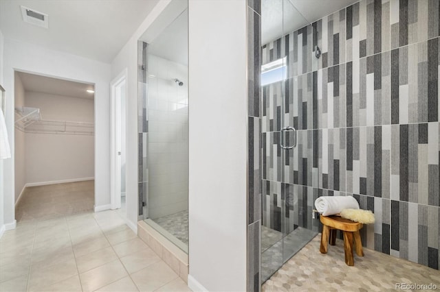 bathroom with visible vents, a spacious closet, a stall shower, tile patterned flooring, and baseboards