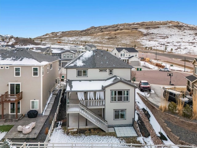 snow covered house featuring stairs, a mountain view, and fence