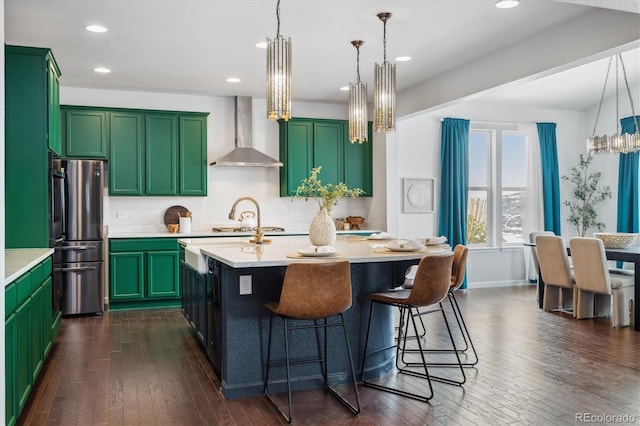 kitchen with freestanding refrigerator, dark wood-style flooring, light countertops, and wall chimney range hood