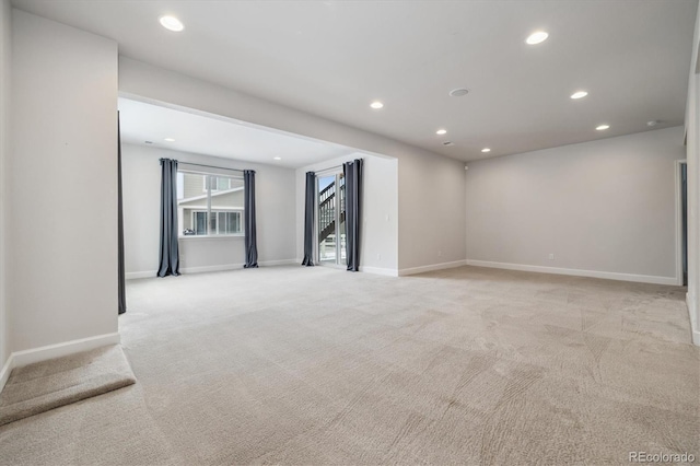 unfurnished room featuring recessed lighting, light colored carpet, stairway, and baseboards