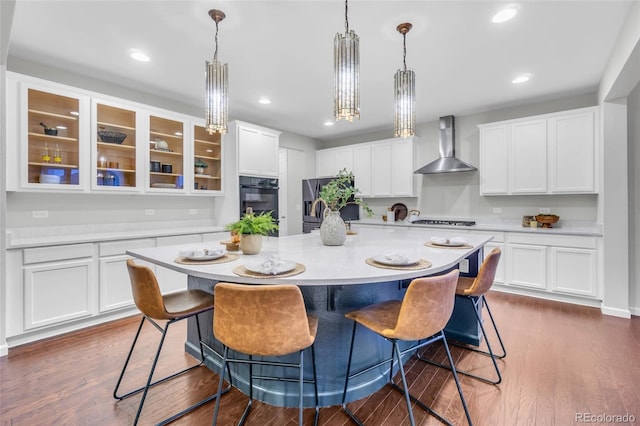 kitchen featuring stainless steel fridge with ice dispenser, light countertops, gas cooktop, wall chimney exhaust hood, and white cabinetry