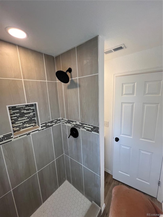 bathroom featuring hardwood / wood-style flooring and tiled shower