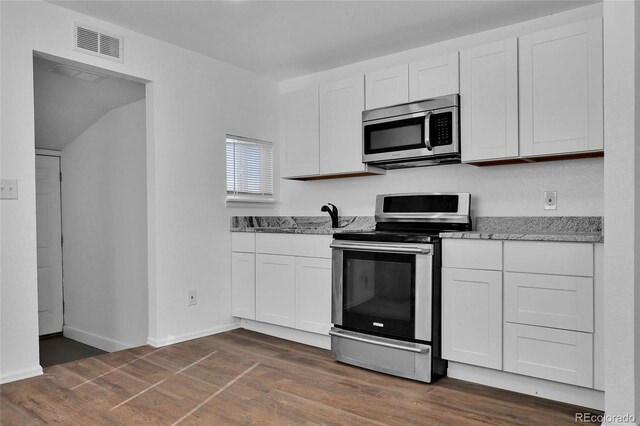 kitchen with stainless steel appliances, dark wood-type flooring, white cabinets, and light stone counters