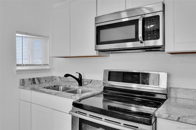 kitchen featuring light stone countertops, white cabinetry, appliances with stainless steel finishes, and sink