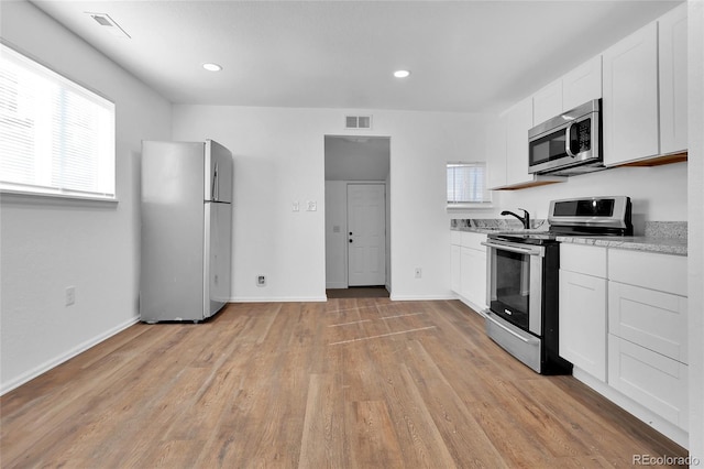 kitchen featuring stainless steel appliances, white cabinetry, and light wood-type flooring